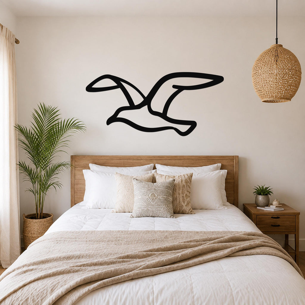 Black metal seagull wall art with a silhouette design, mounted above a wooden bed in a neutral bedroom.