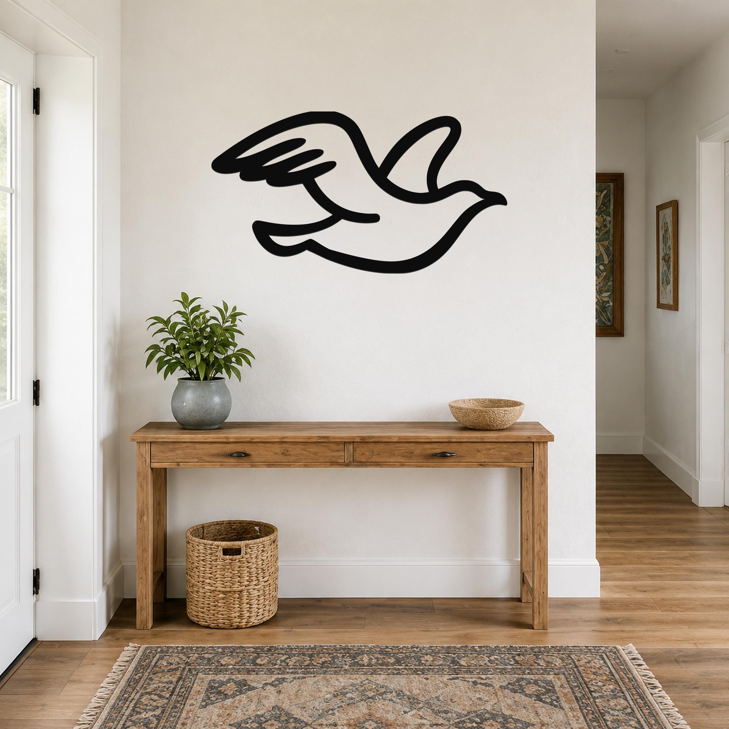 Black metal seagull wall art with motion-line cutouts, mounted above a wooden console table in a bright entryway.