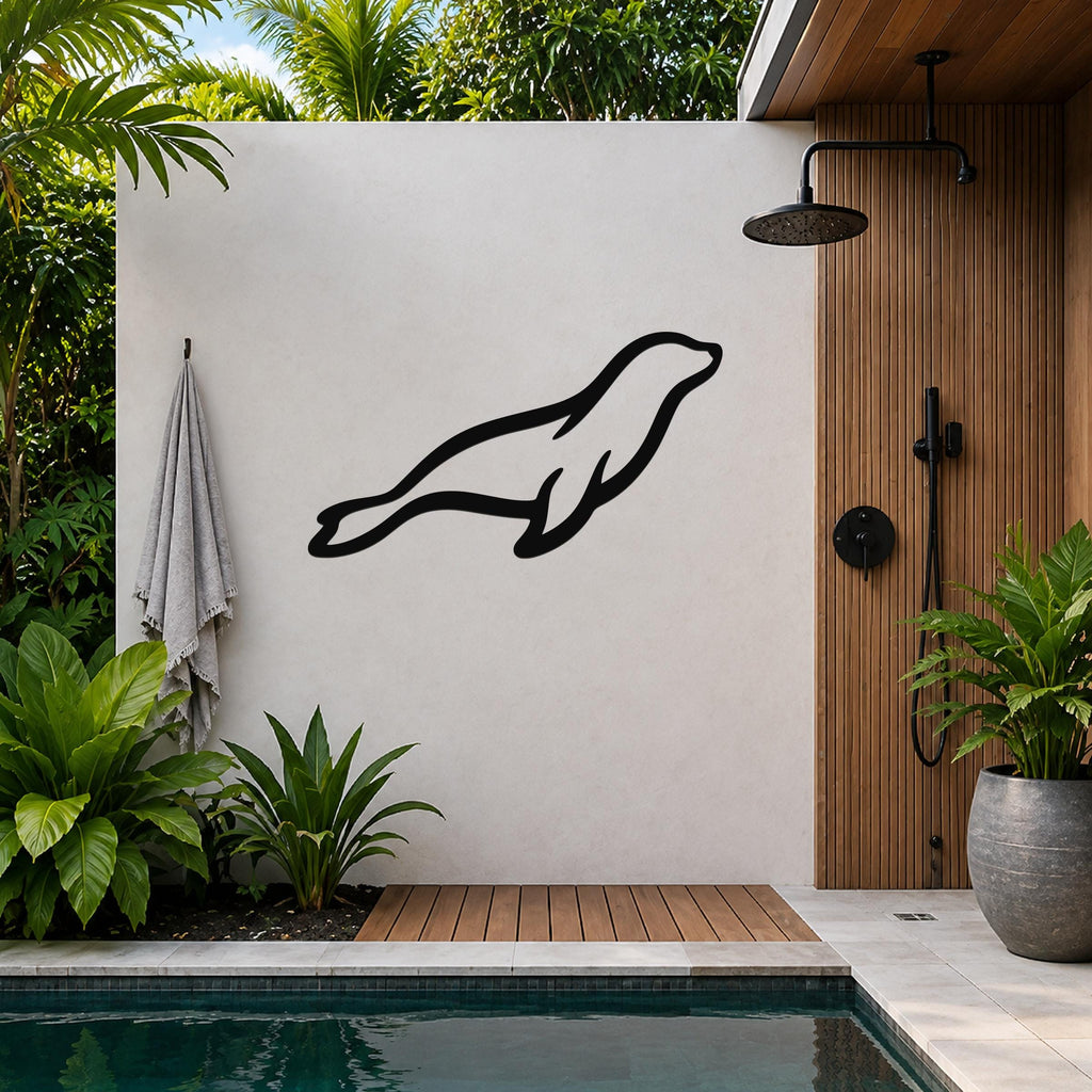 Black metal sea lion wall art silhouette mounted on a light-colored outdoor wall beside a wooden shower enclosure and pool.