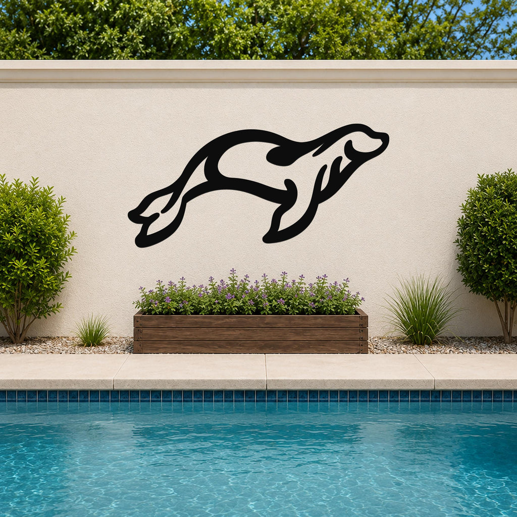 Black metal sea lion wall art in a leaping silhouette, mounted on an outdoor wall above a planter and pool.