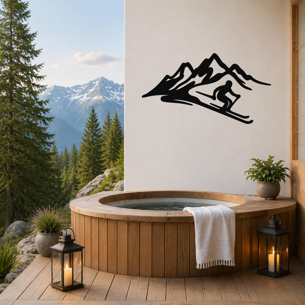 Black metal skier and mountain wall art with fluid motion cutouts, mounted on a white wall above a wooden hot tub on a deck with mountain views.