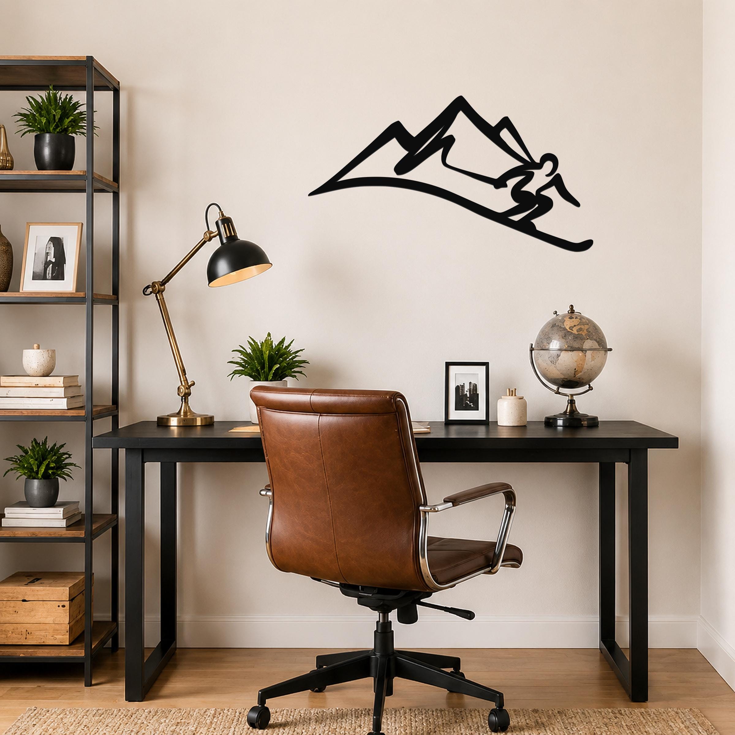 Black metal wall art silhouette of a skier in motion above a mountain, mounted on a wall above a black desk in a home office.