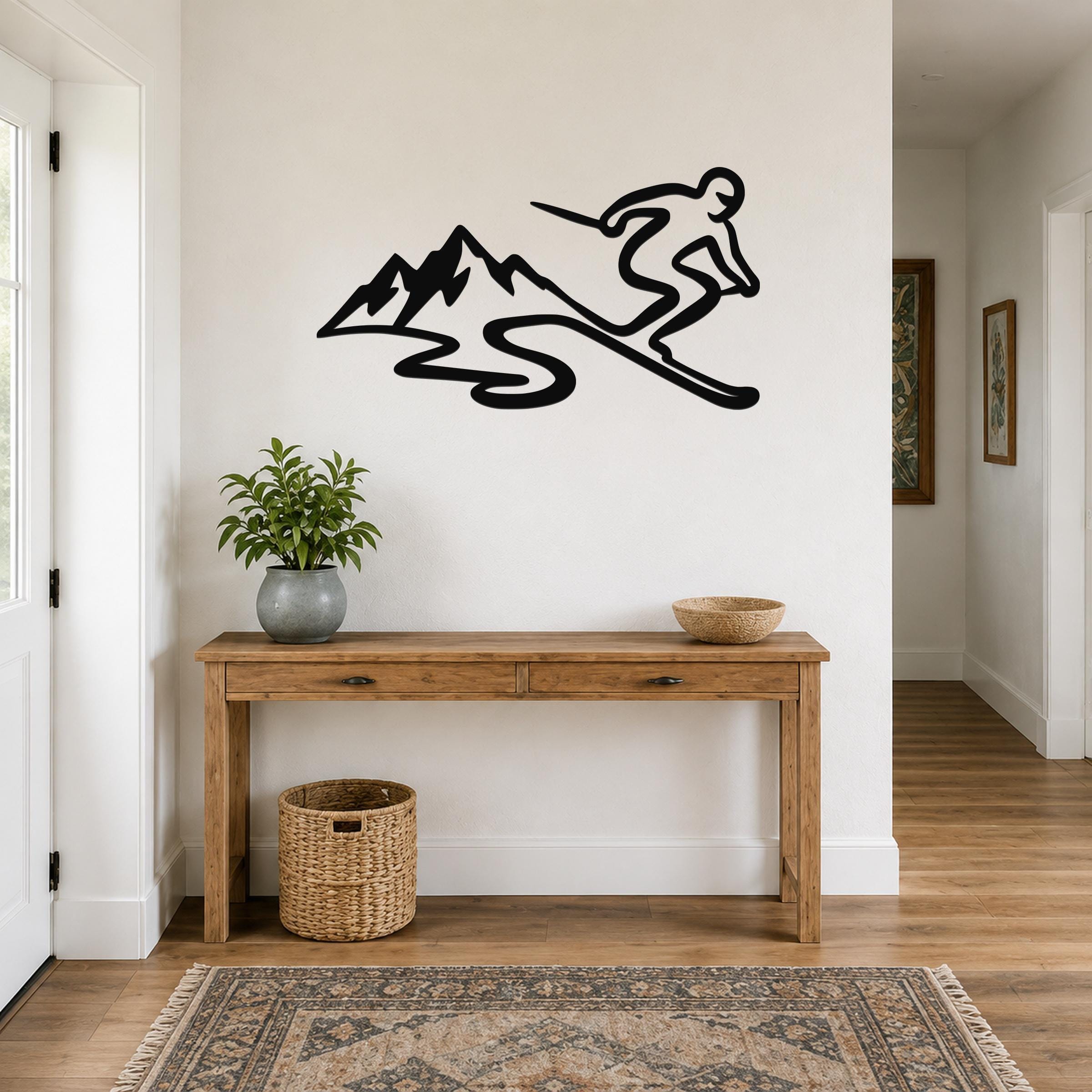 Black metal skier and mountain wall art silhouette mounted above a wooden console table in a hallway.