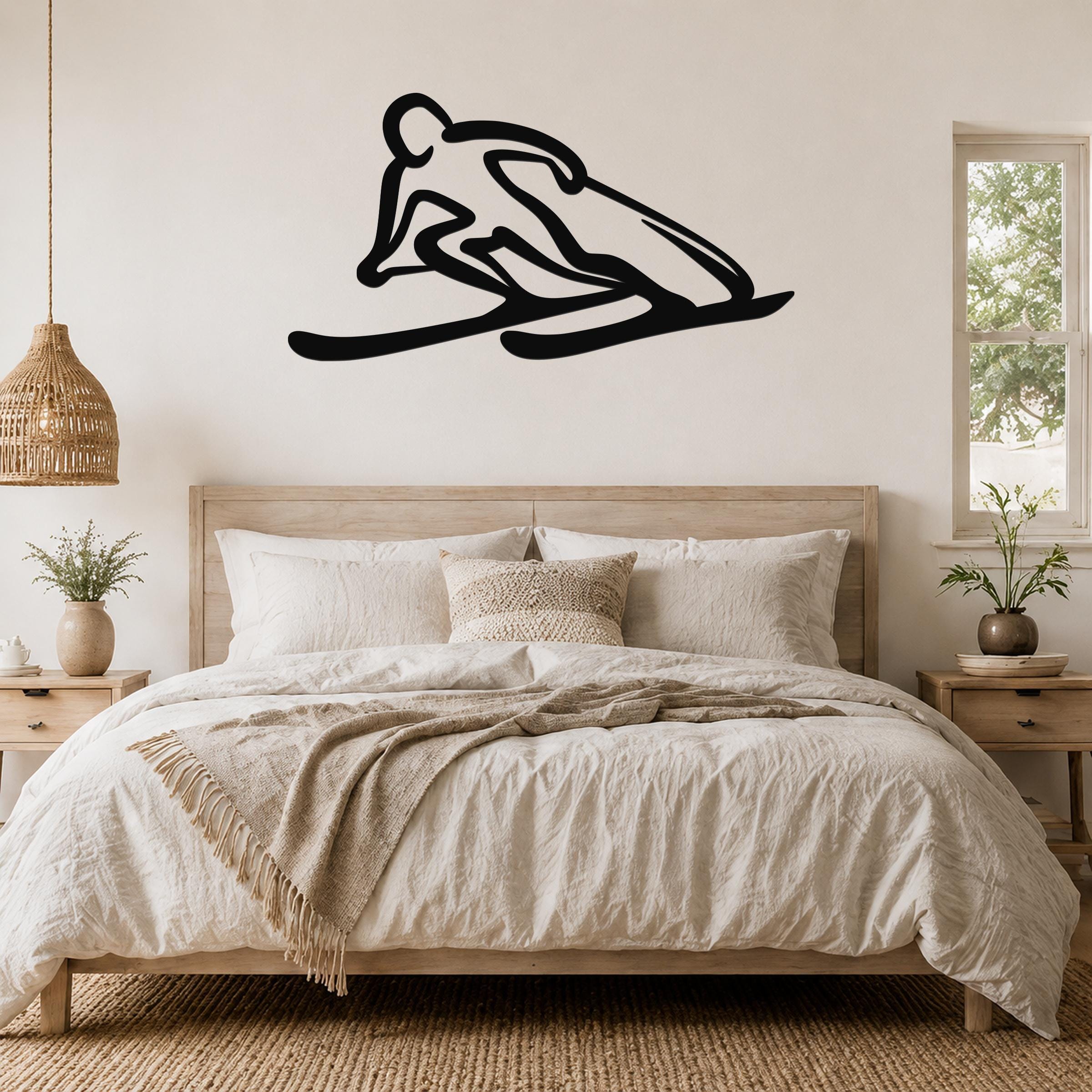 Black metal wall art of a minimalist skier silhouette, mounted above a bed in a neutral bedroom.