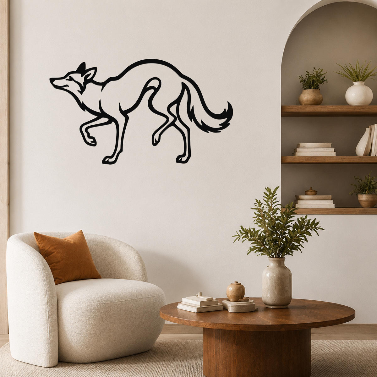 Black metal coyote wall art in a running silhouette, mounted on a living room wall above a white armchair.