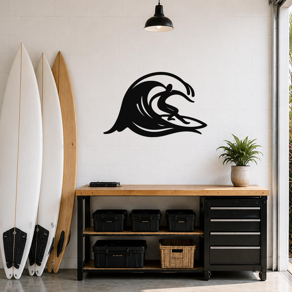 Black metal wall art in a surfer riding a wave silhouette, mounted on a white brick wall above a wooden workbench in a garage.