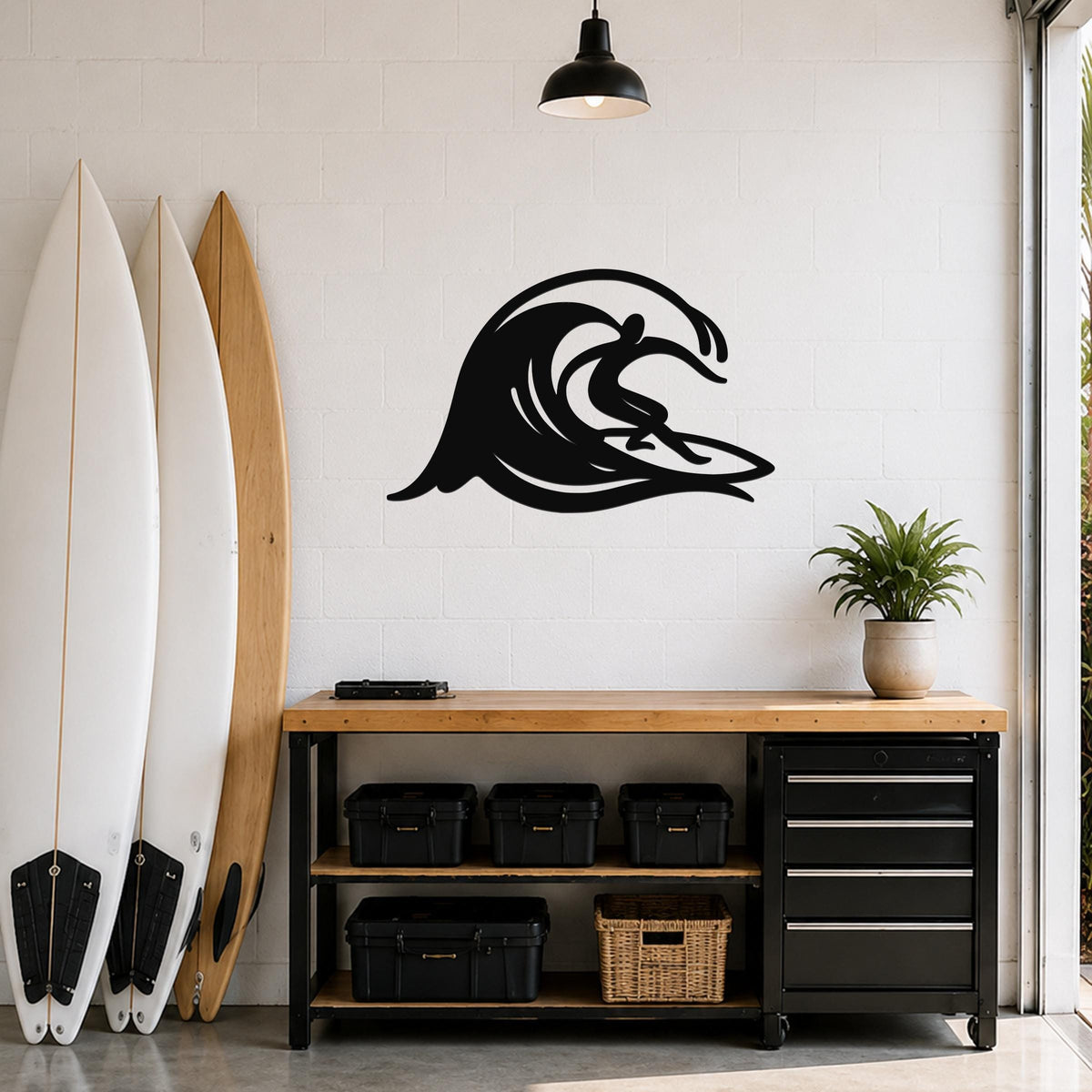Black metal wall art in a surfer riding a wave silhouette, mounted on a white brick wall above a wooden workbench in a garage.