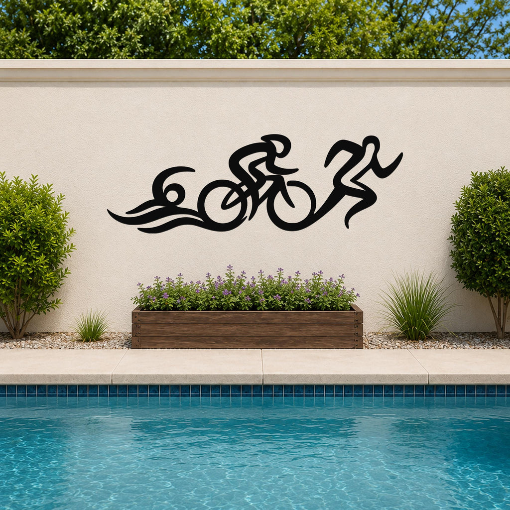Black metal triathlon wall art with flowing cutout design of swim, bike, and run, mounted on an outdoor wall above a poolside planter.
