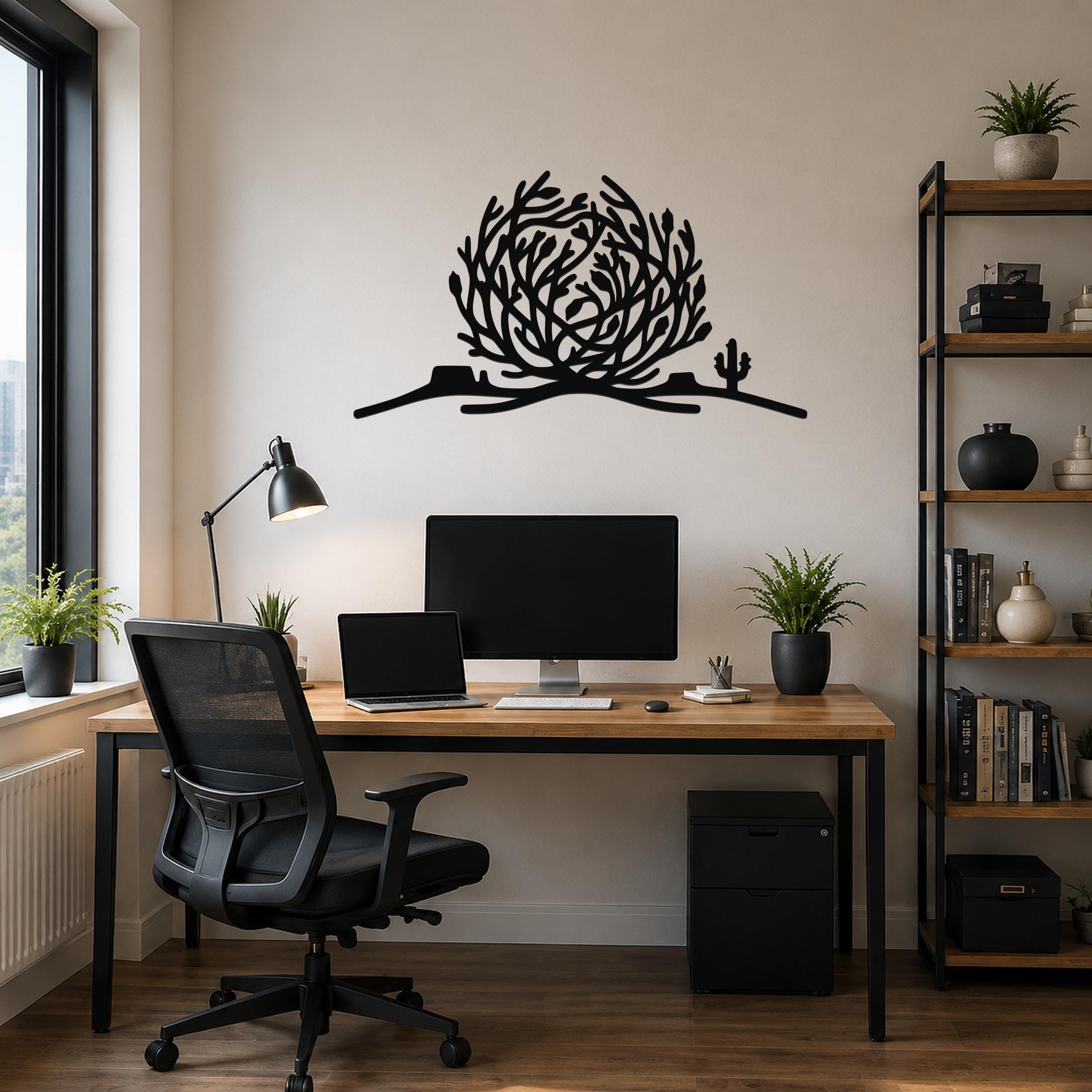 Black metal wall art silhouette of a tumbleweed and cactus, mounted above a wooden desk in a home office.