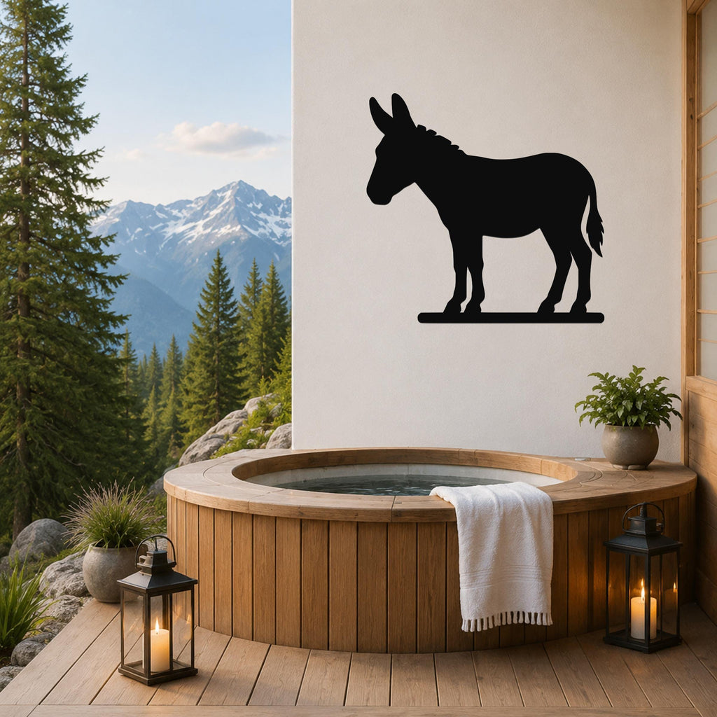 Black metal donkey silhouette wall art mounted on a white wall above a wooden hot tub on a mountain-view patio.