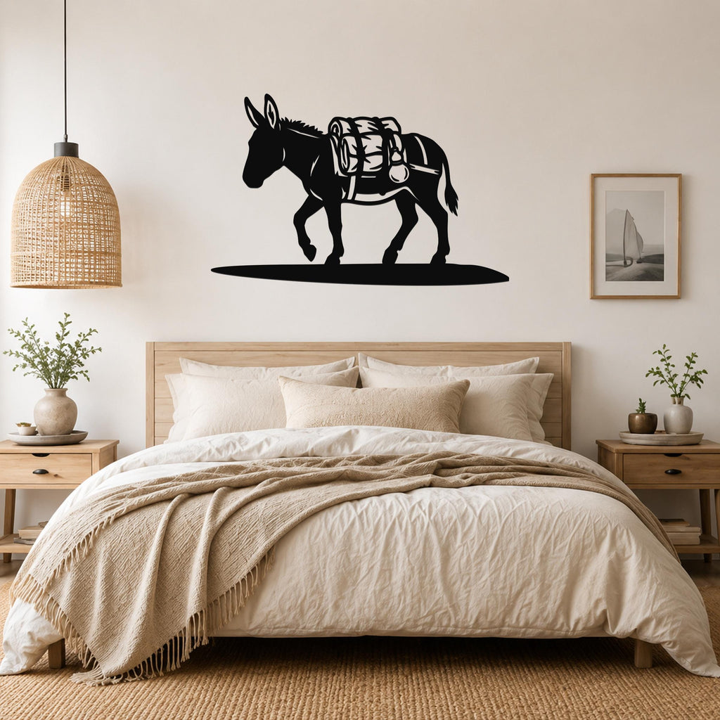 Black metal burro wall art silhouette with saddle and pack, mounted above a bed in a neutral bedroom.