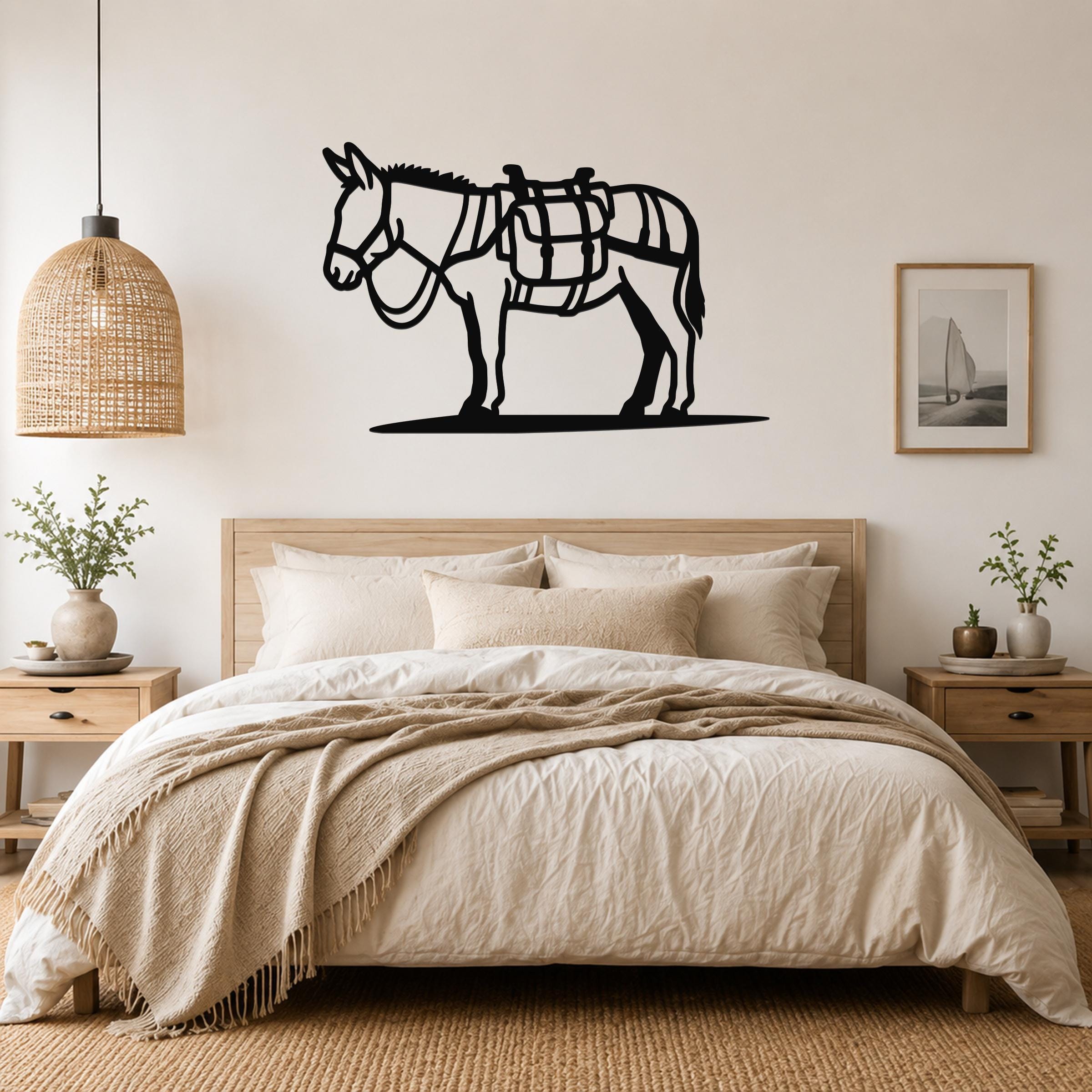 Black metal burro wall art with saddle cutouts, mounted above a bed in a neutral bedroom.