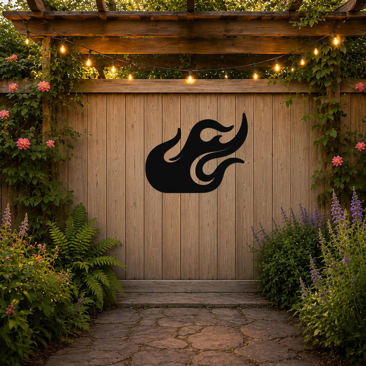 Black metal flame wall art with flowing cutout design, mounted on a wooden fence in a garden setting.
