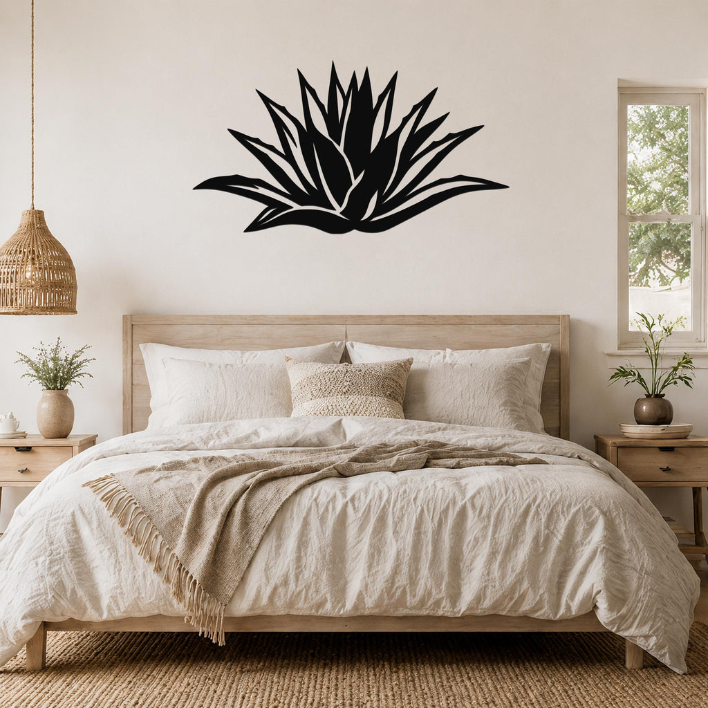 Black metal agave wall art with leaf cutouts, mounted above a bed in a neutral bedroom.