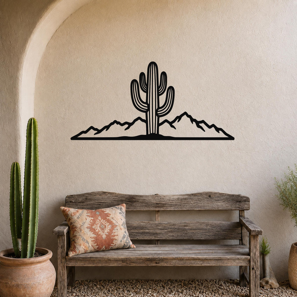 Black metal wall art silhouette of a saguaro cactus and mountain range, mounted above a wooden bench in a desert-themed entryway.