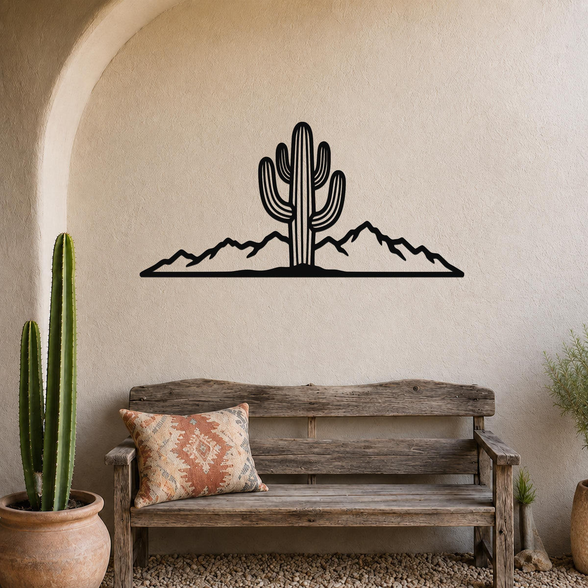 Black metal wall art silhouette of a saguaro cactus and mountain range, mounted above a wooden bench in a desert-themed entryway.