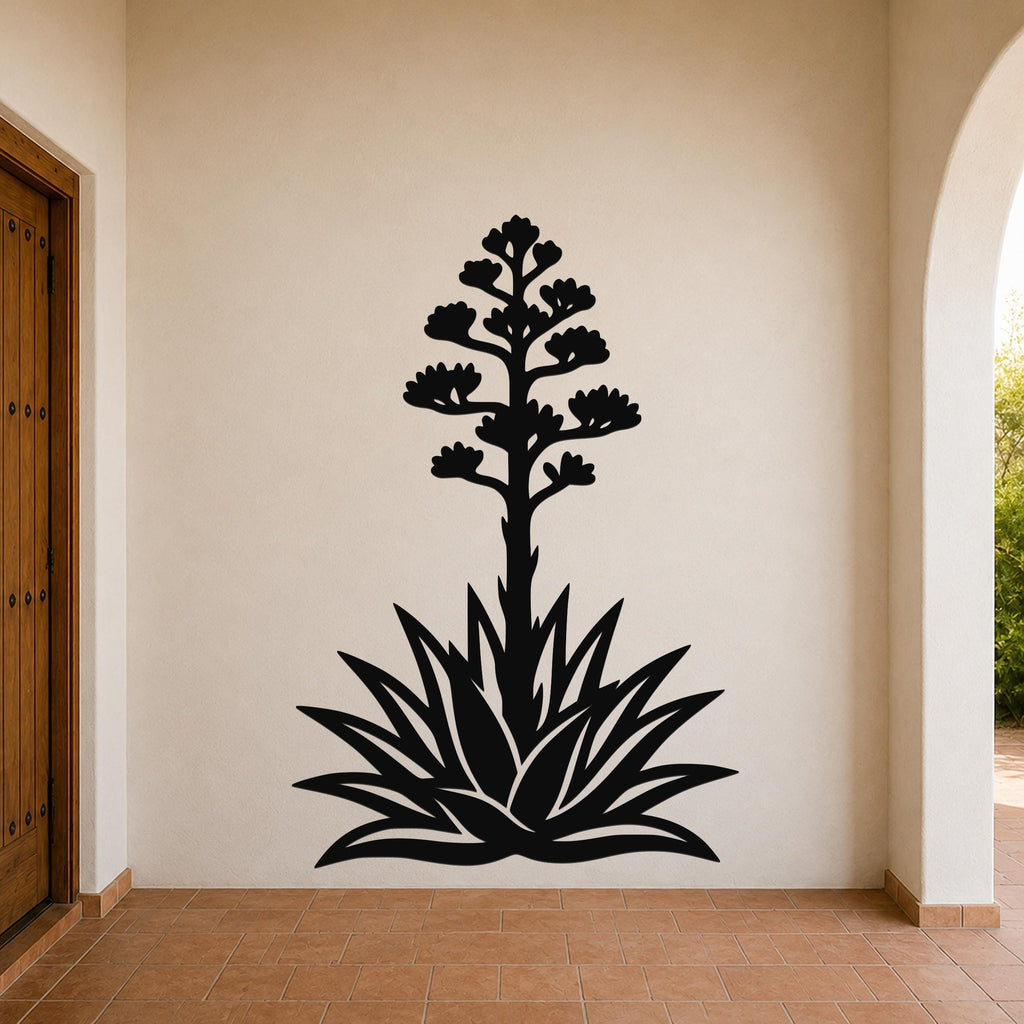 Black metal wall art silhouette of a blooming agave plant with a tall flower stalk and spiky leaves, mounted on a beige wall in a covered entryway.