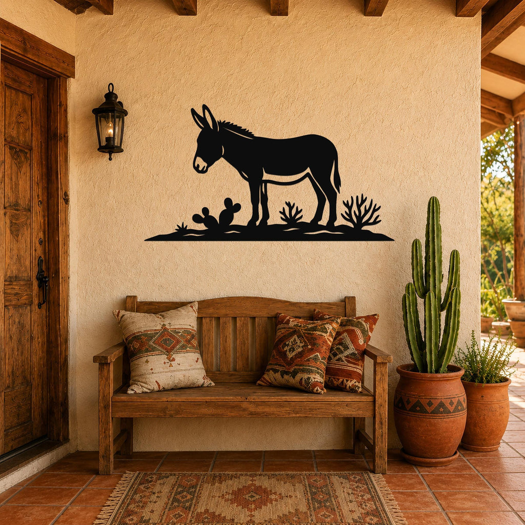 Black metal wall art silhouette of a burro with cacti, mounted on a stucco wall above a wooden bench in a rustic patio entry.