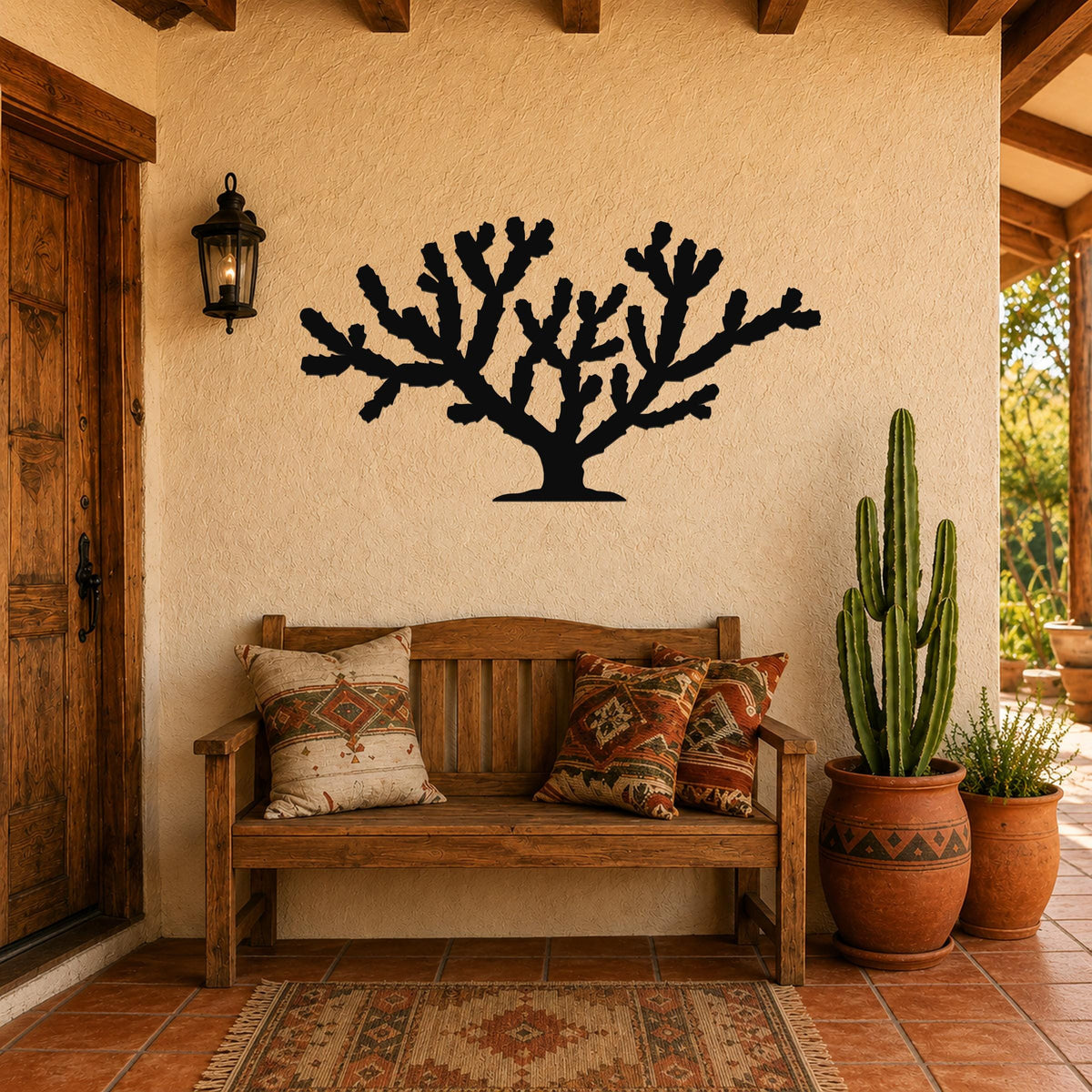 Black metal Cholla cactus wall art silhouette mounted on a stucco wall above a wooden bench in a patio entryway.