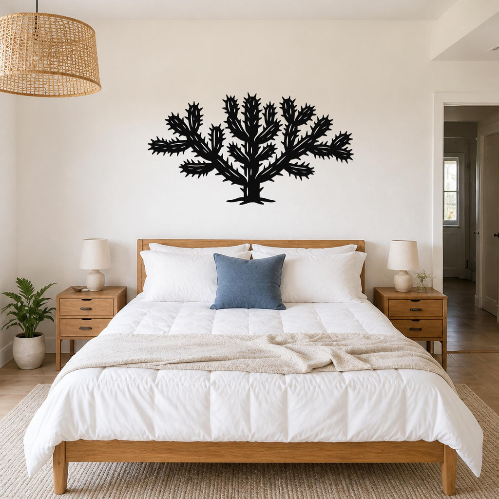 Black metal Cholla cactus wall art with spiky branch cutouts, mounted above a wooden bed in a bedroom.