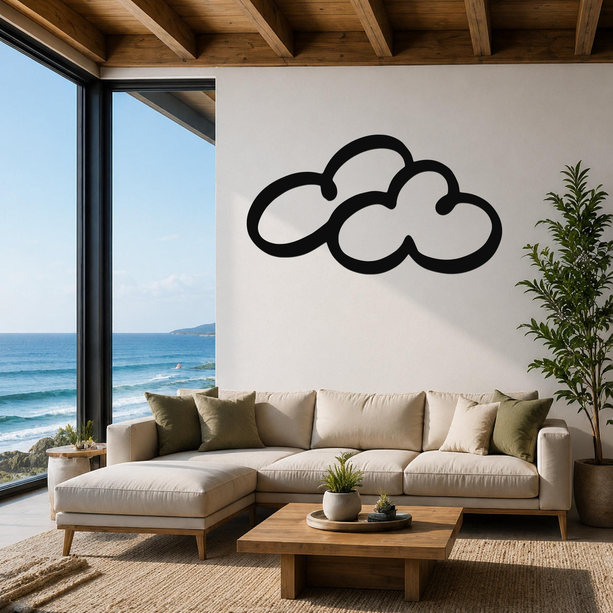 Black metal cloud wall art with a bold silhouette design, mounted on a white wall above a beige sectional sofa in a living room with ocean views.