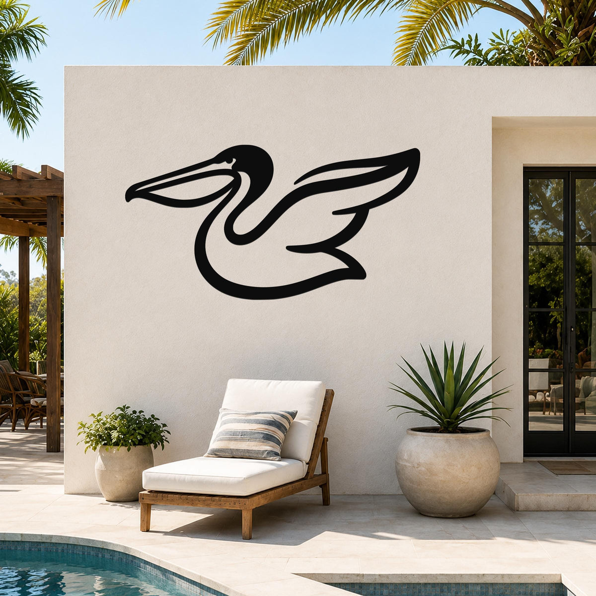 Black metal pelican wall art with a flowing silhouette, mounted on an outdoor patio wall above a lounge chair and potted plants.