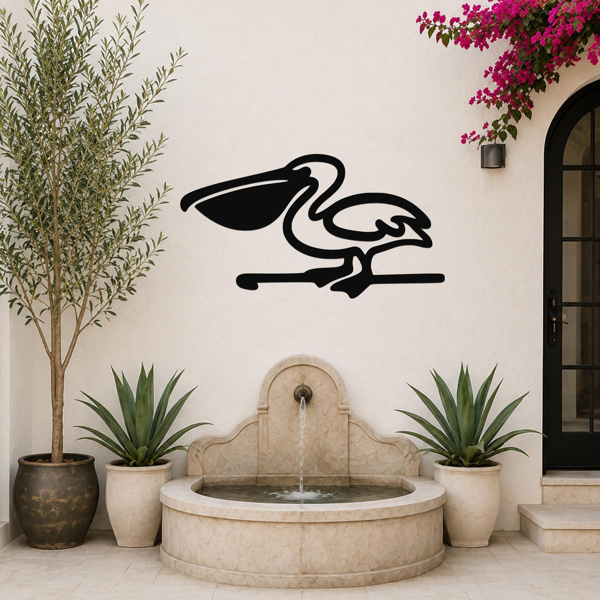 Black metal pelican wall art in silhouette style, mounted on a white outdoor wall above a stone fountain, flanked by potted plants and a flowering vine.