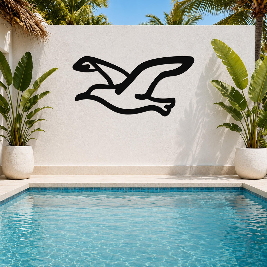Black metal seagull wall art with a flowing silhouette, mounted on a white outdoor wall above a pool, flanked by potted plants.