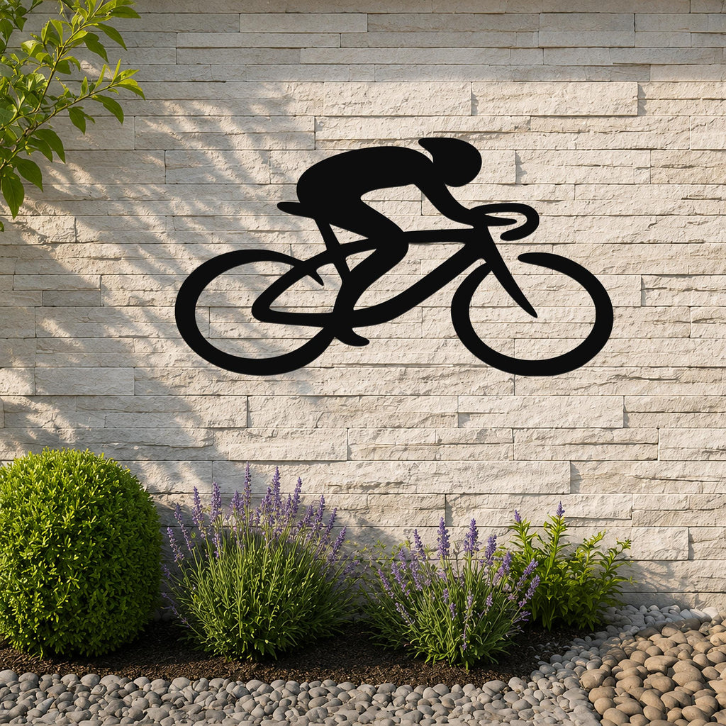 Black metal wall art in a bold silhouette of a cyclist on a bike, mounted on a light stone wall above a garden bed with lavender and pebbles.