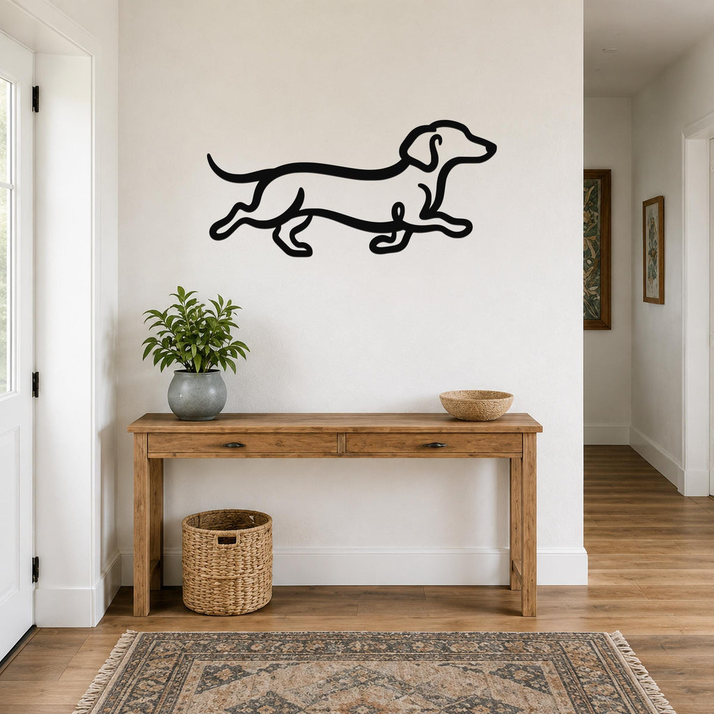Black metal dachshund wall art with a continuous line silhouette, mounted above a wooden console table in a hallway.