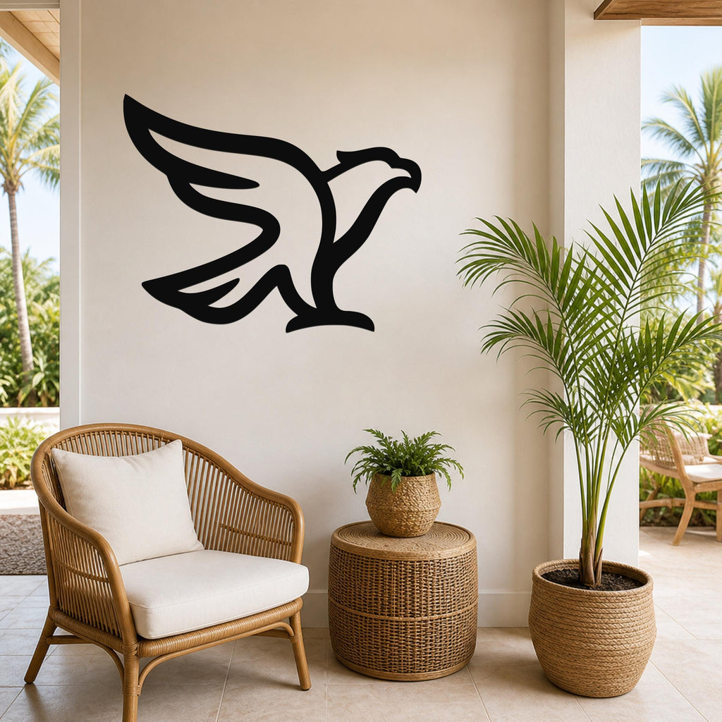 Black metal eagle wall art with a bold silhouette design, mounted on a light-colored wall above a wicker chair and potted plants in a bright indoor-outdoor space.