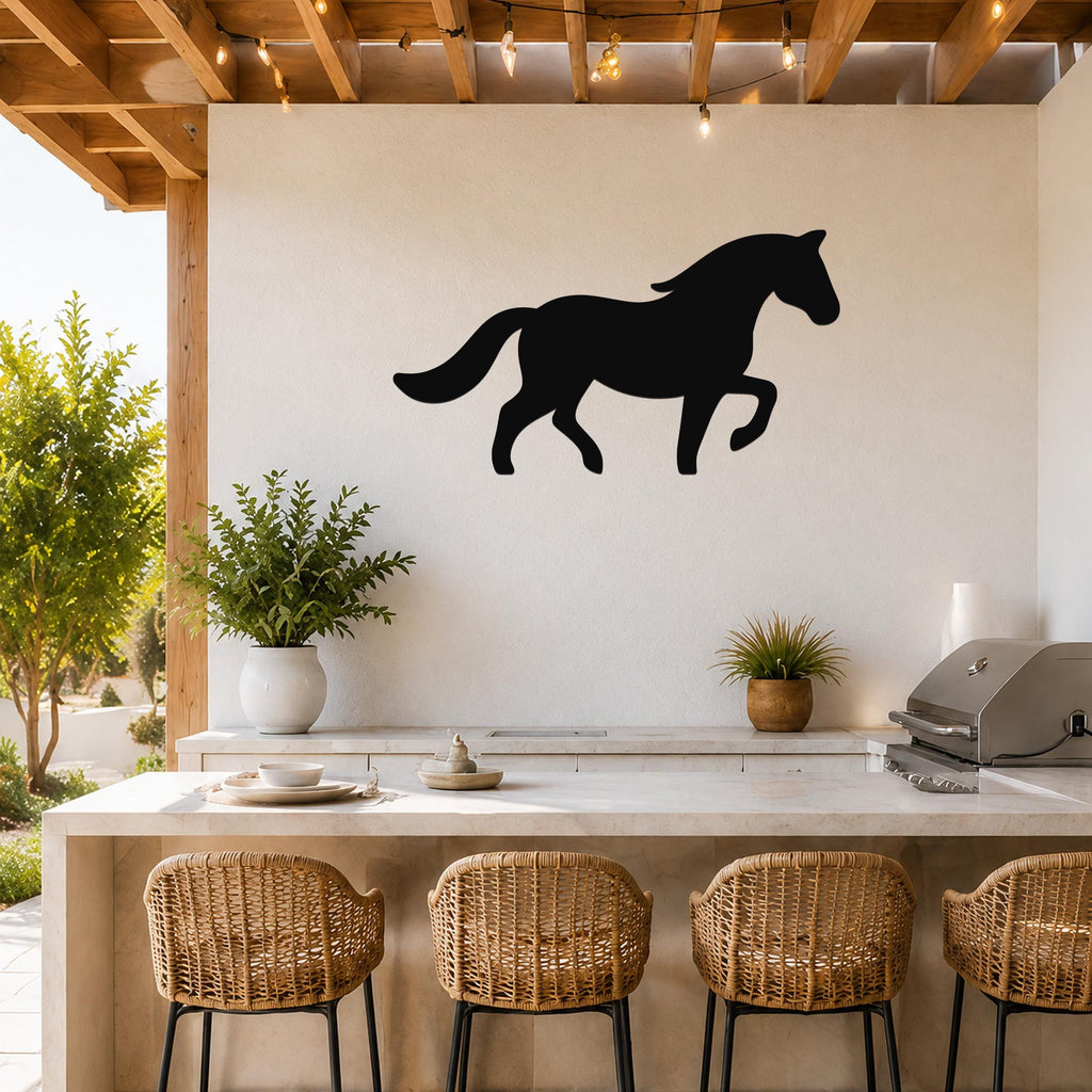 Black metal horse silhouette wall art mounted on a white wall above a kitchen counter with wicker bar stools and string lights.