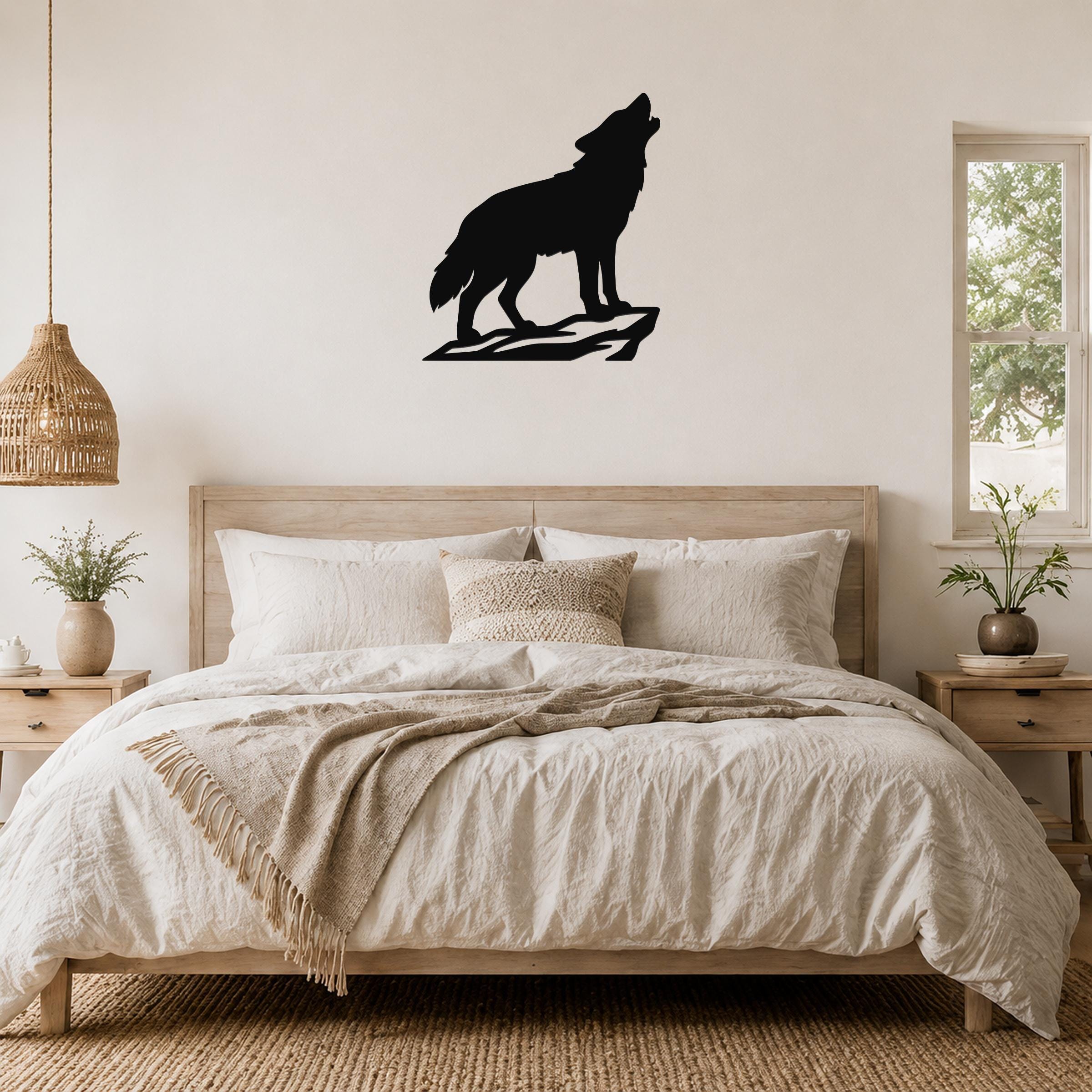 Black metal coyote wall art silhouette howling on a rock, mounted above a bed in a neutral bedroom.