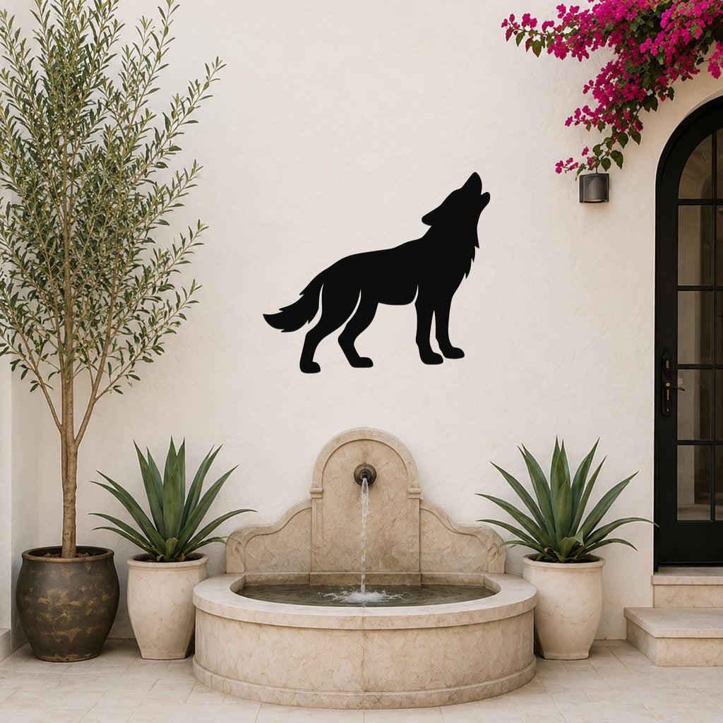 Black metal coyote silhouette wall art mounted on a white stucco wall above a stone fountain in a patio setting.