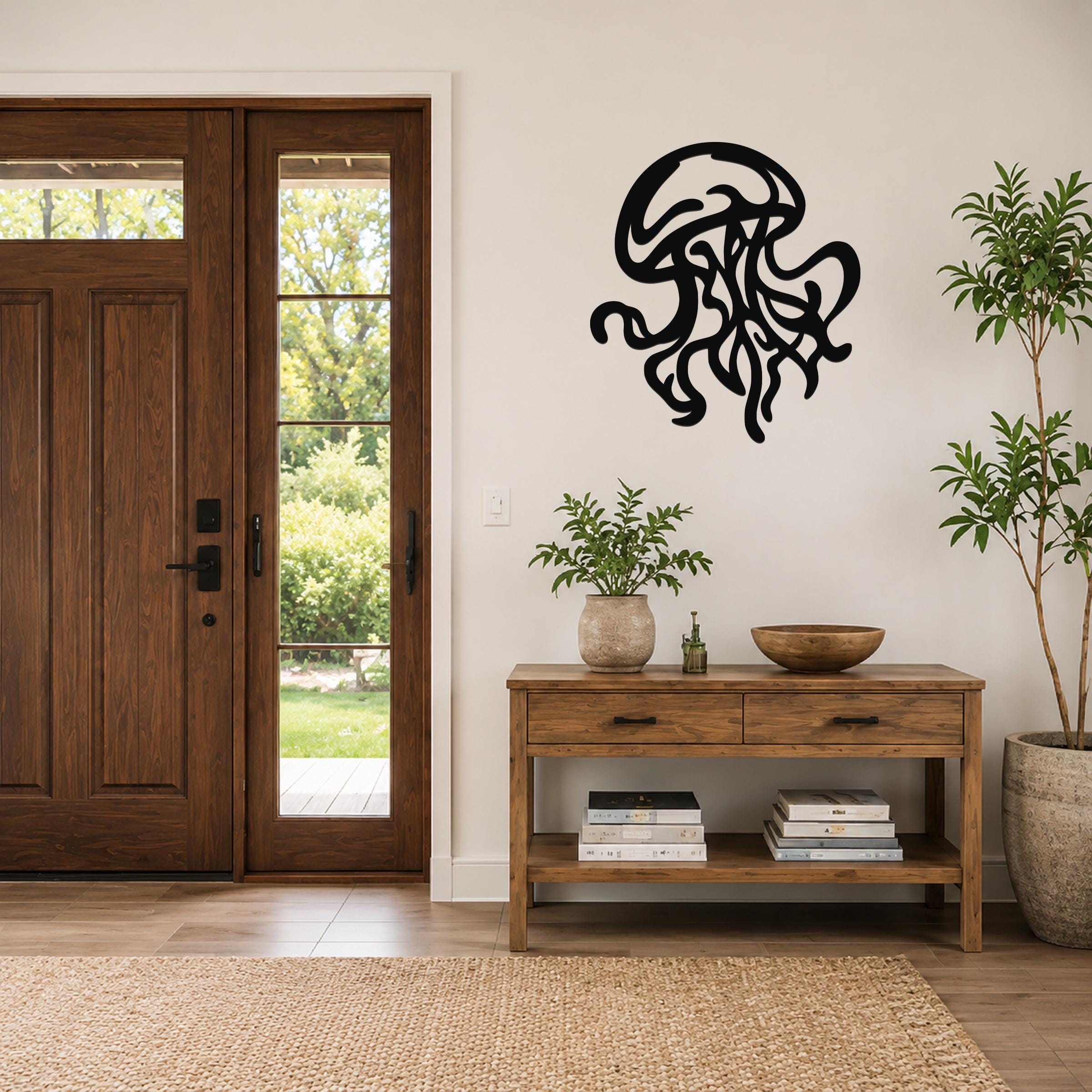 Black metal jellyfish wall art with flowing tentacle cutouts, mounted on a white wall above a wooden console table in a modern entryway.