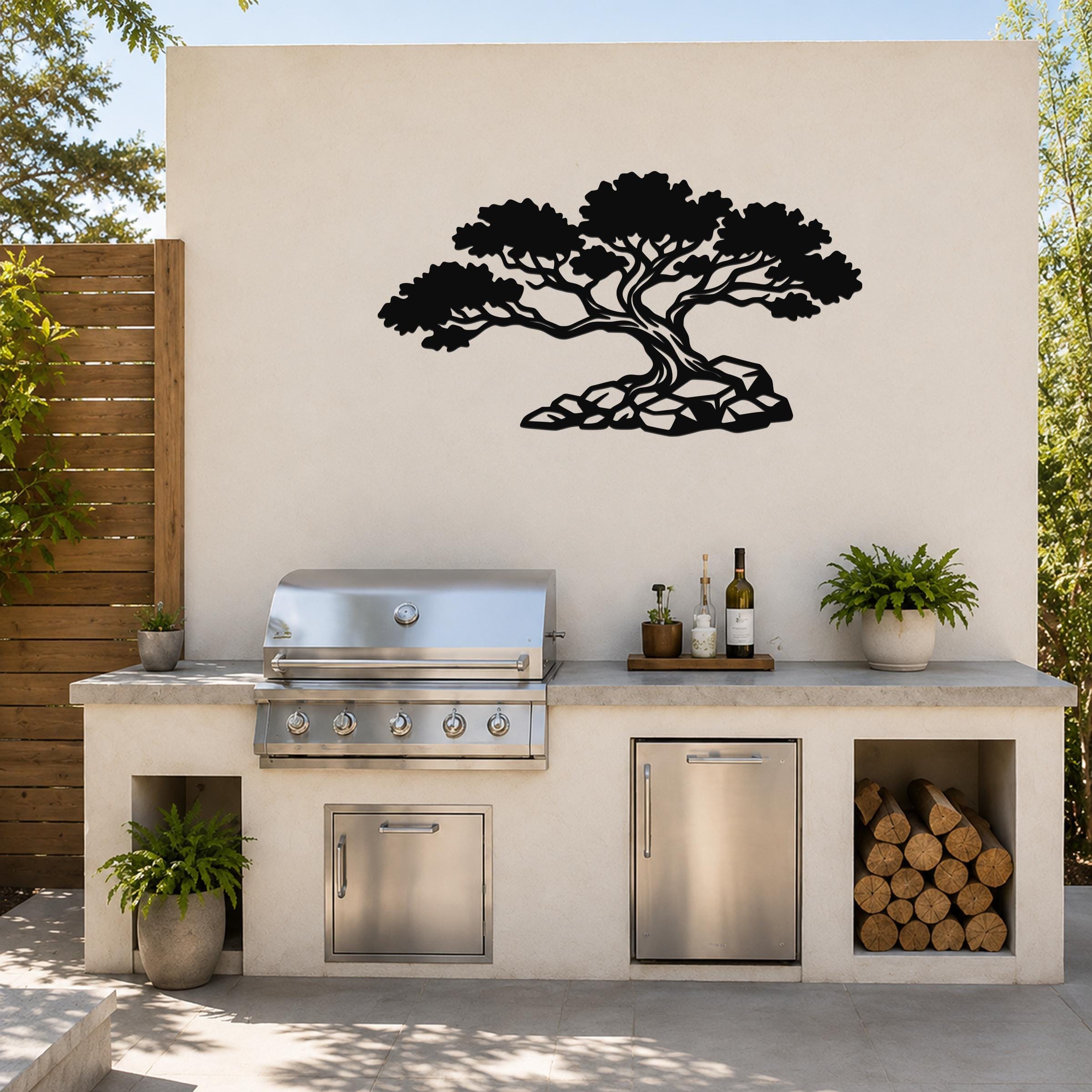 Black metal wall art in a bonsai tree silhouette with visible branch and root cutouts, mounted on a light-colored outdoor wall above a kitchen counter.