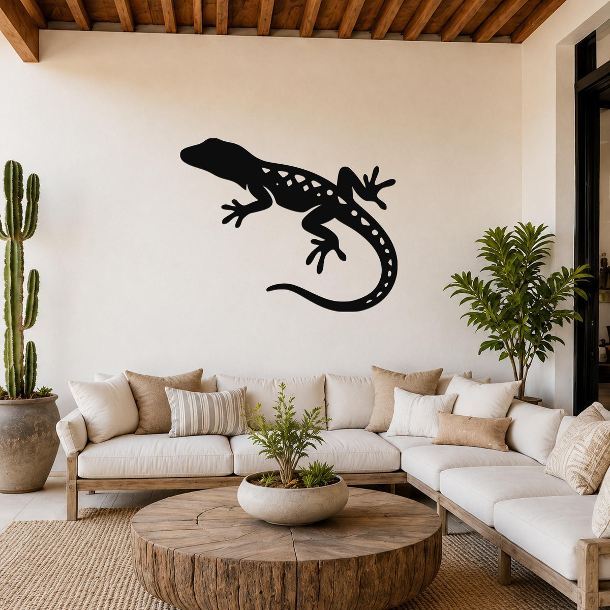Black metal lizard wall art with internal cutout details, mounted on a living room wall above a white sofa.