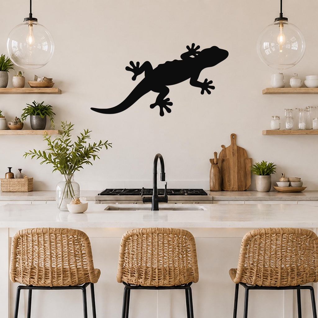 Black metal gecko wall art silhouette mounted on a kitchen wall above a counter, with wicker bar stools and open shelves visible below.