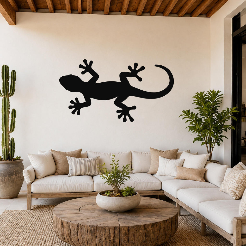 Black metal gecko wall art silhouette mounted on a living room wall above a white sofa.