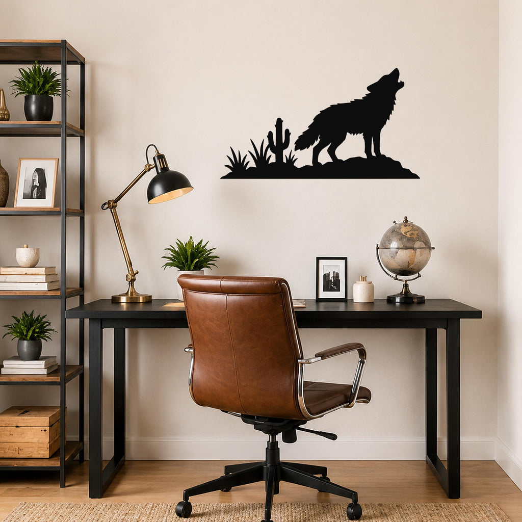 Black metal wall art silhouette of a coyote howling on a rock with cactus and desert plants, mounted above a black desk in a home office.
