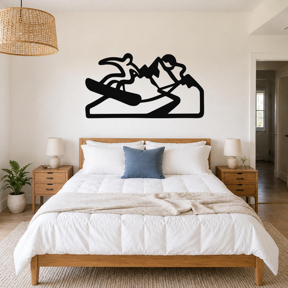 Black metal wall art silhouette of a snowboarder in motion, mounted above a bed in a bedroom.