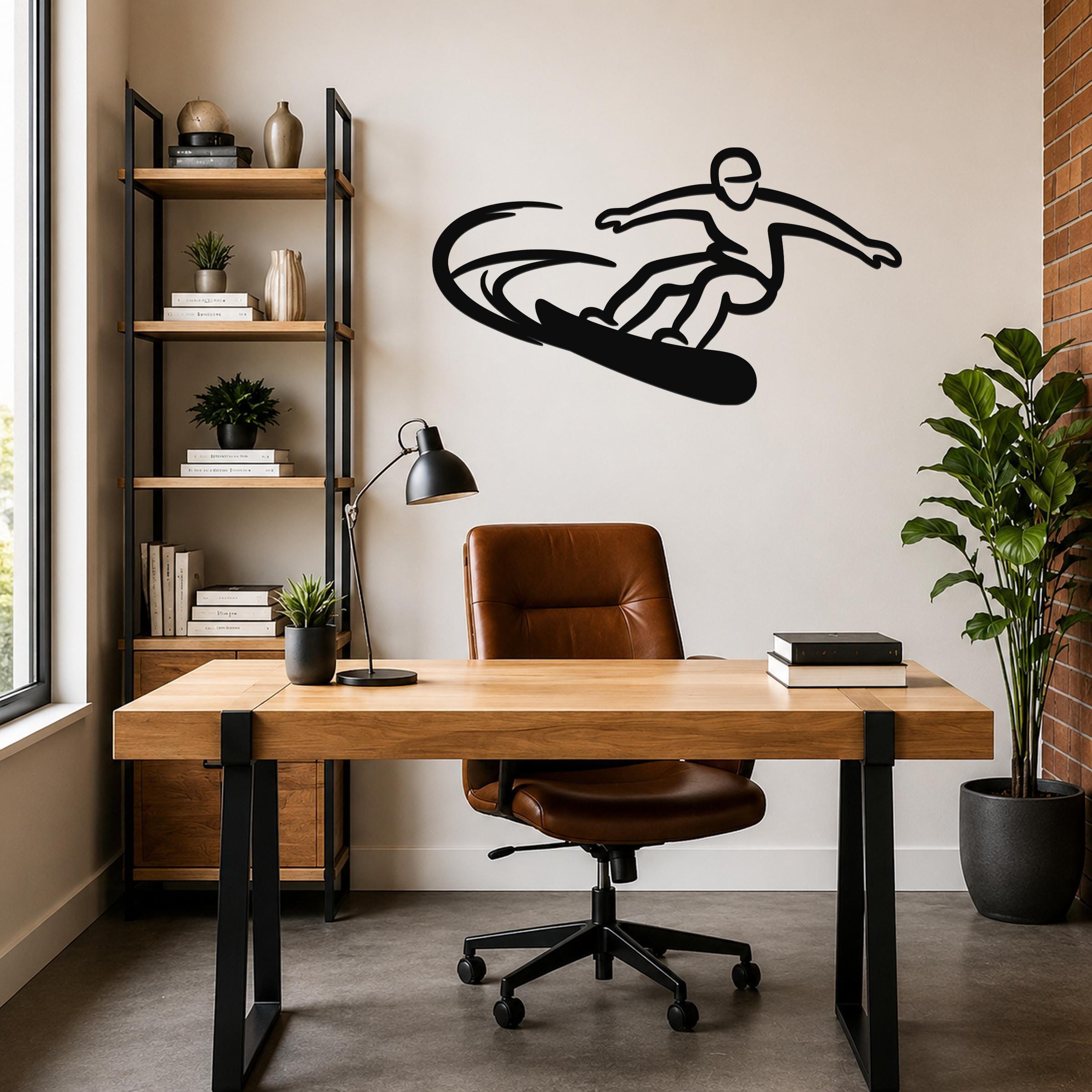 Black metal wall art silhouette of a snowboarder in motion, mounted above a wooden desk in a modern home office.