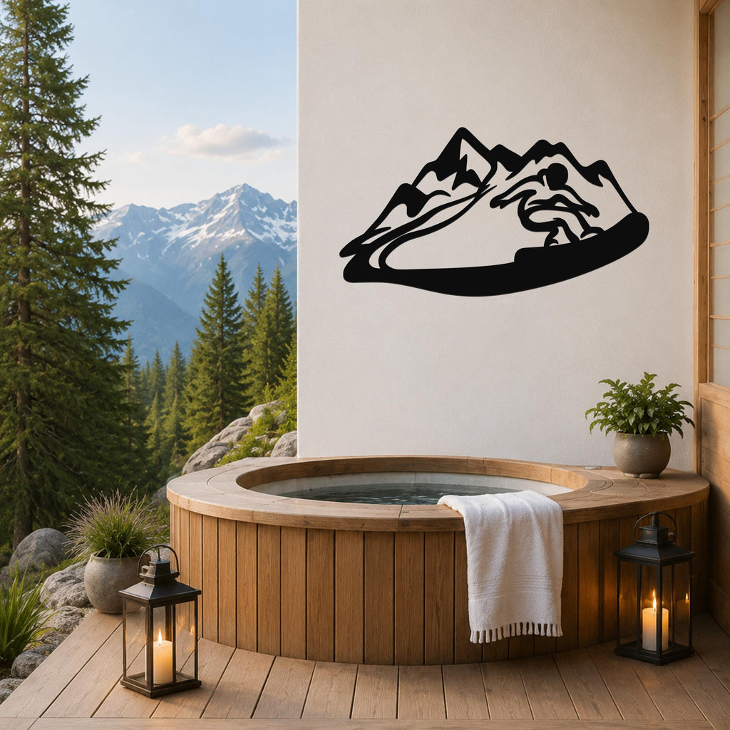Black metal wall art featuring a snowboarder silhouette in motion against a mountain range, mounted on a light-colored wall above a wooden hot tub on a deck with a mountain view.