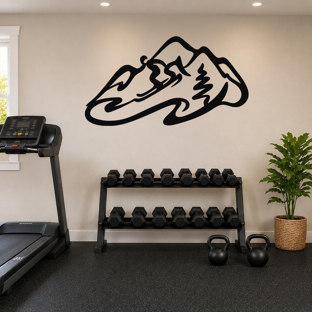 Black metal wall art in a mountain and skier silhouette design, mounted on a light-colored wall above a dumbbell rack in a home gym.