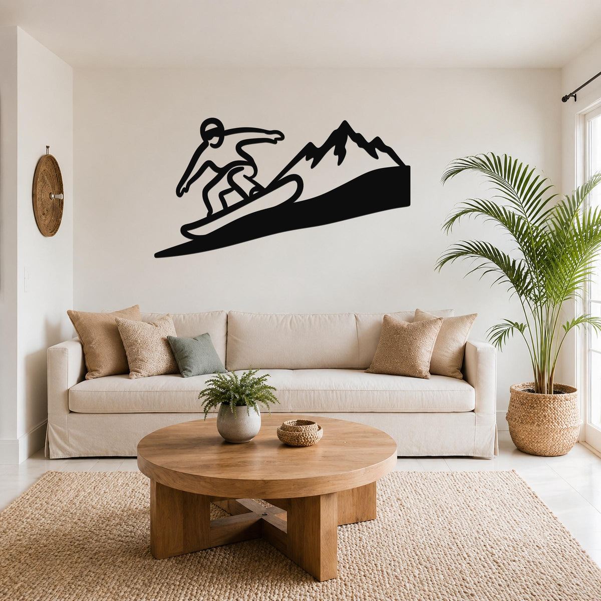 Black metal wall art silhouette of a snowboarder on a wave with mountains, mounted above a sofa in a living room.