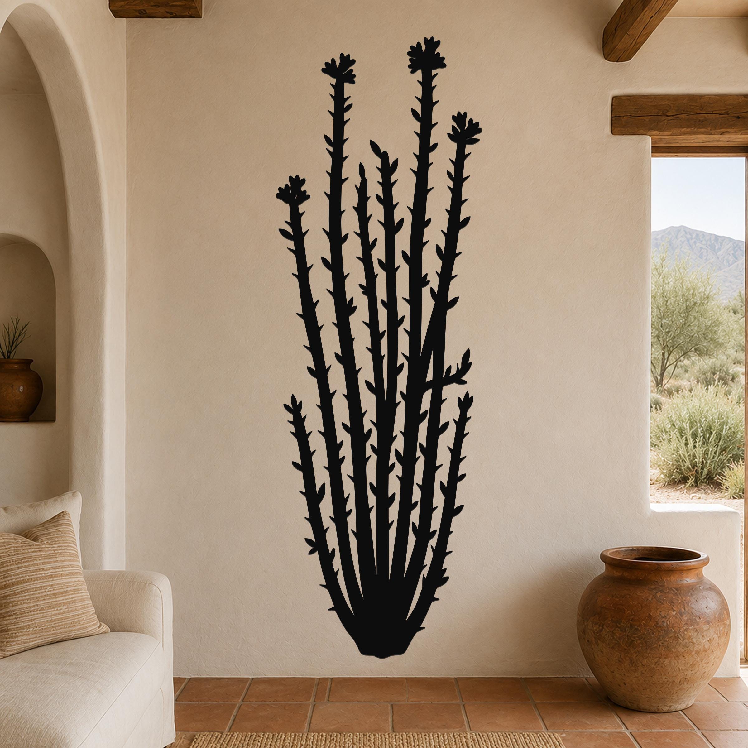 Black metal ocotillo wall art with tubular flower cutouts, mounted on a beige living room wall above a sofa.