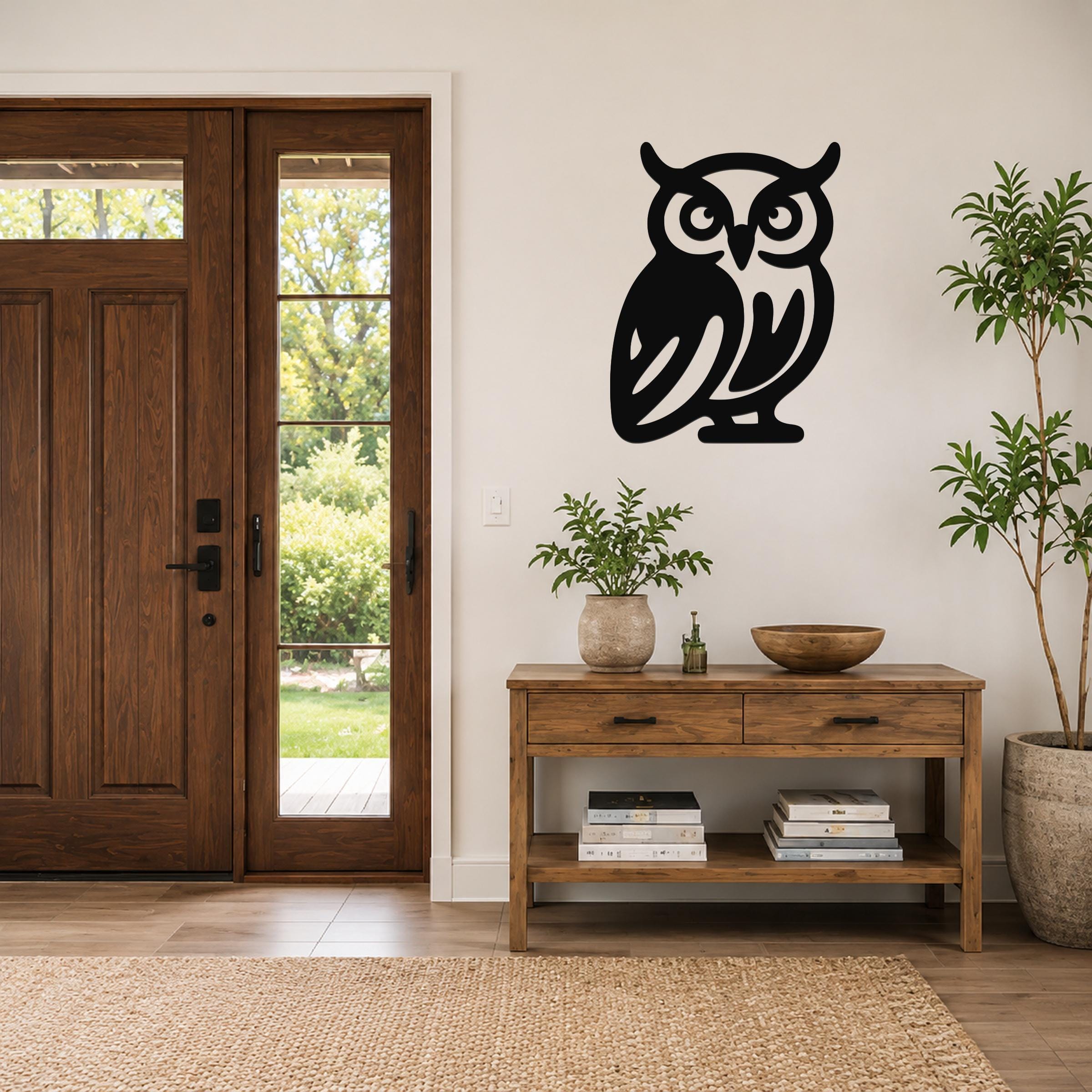 Black metal owl wall art with cutout details, mounted on a light-colored wall above a wooden console table in a living room.