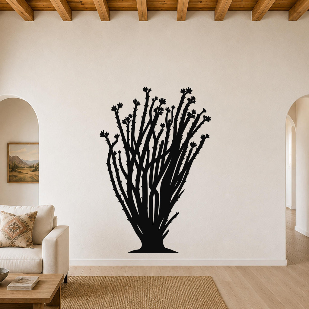 Black metal ocotillo wall art with branching stems and flower cutouts, mounted on a living room wall above a sofa.