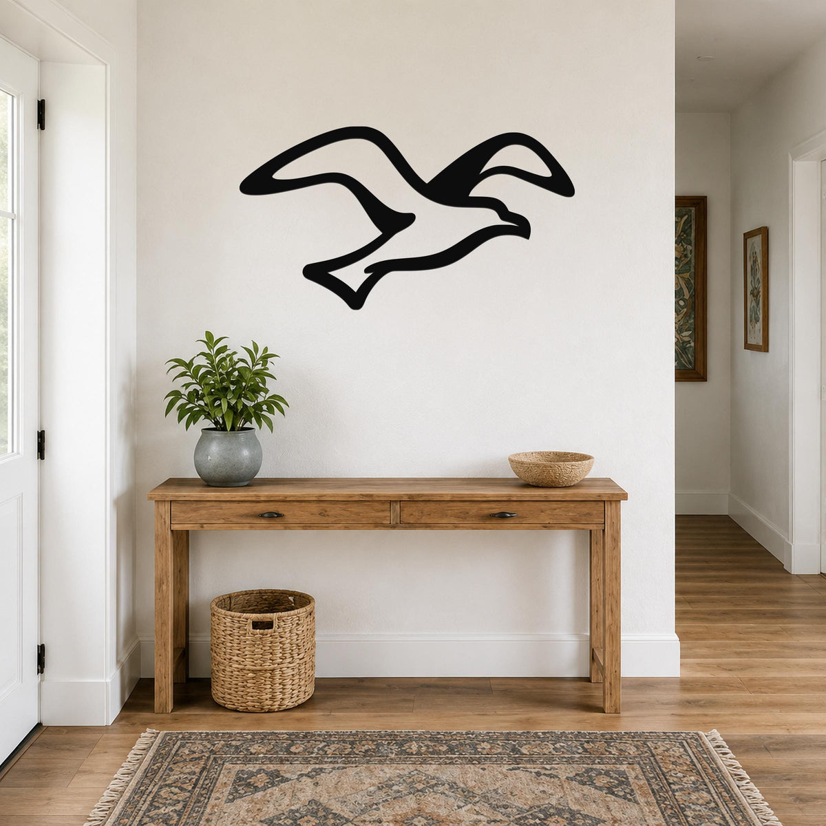 Black metal seagull wall art with motion-line cutouts, mounted above a wooden console table in a bright entryway.