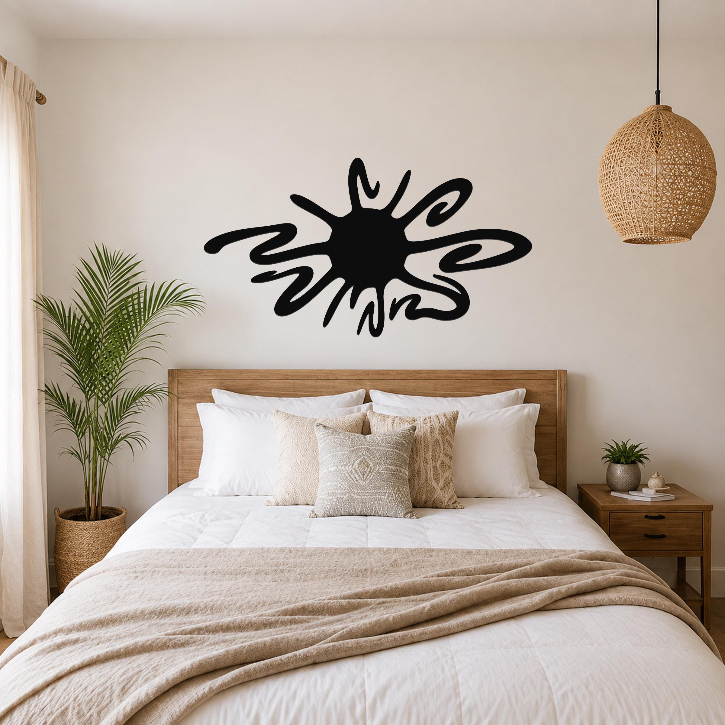 Black metal wall art in a sea urchin silhouette with flowing spines, mounted above a wooden bed in a neutral bedroom.